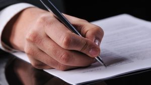 Dwóch współpracowników podpisujących umowę zlecenie przy biurku